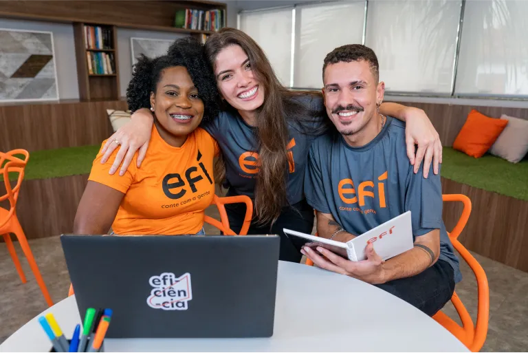 Três colaboradores do Efí Bank se abraçando